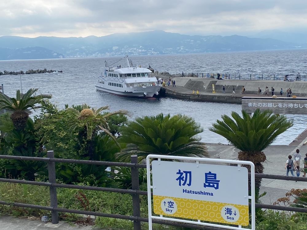 入港したイルドバカンスプレミアと初島駅看板
